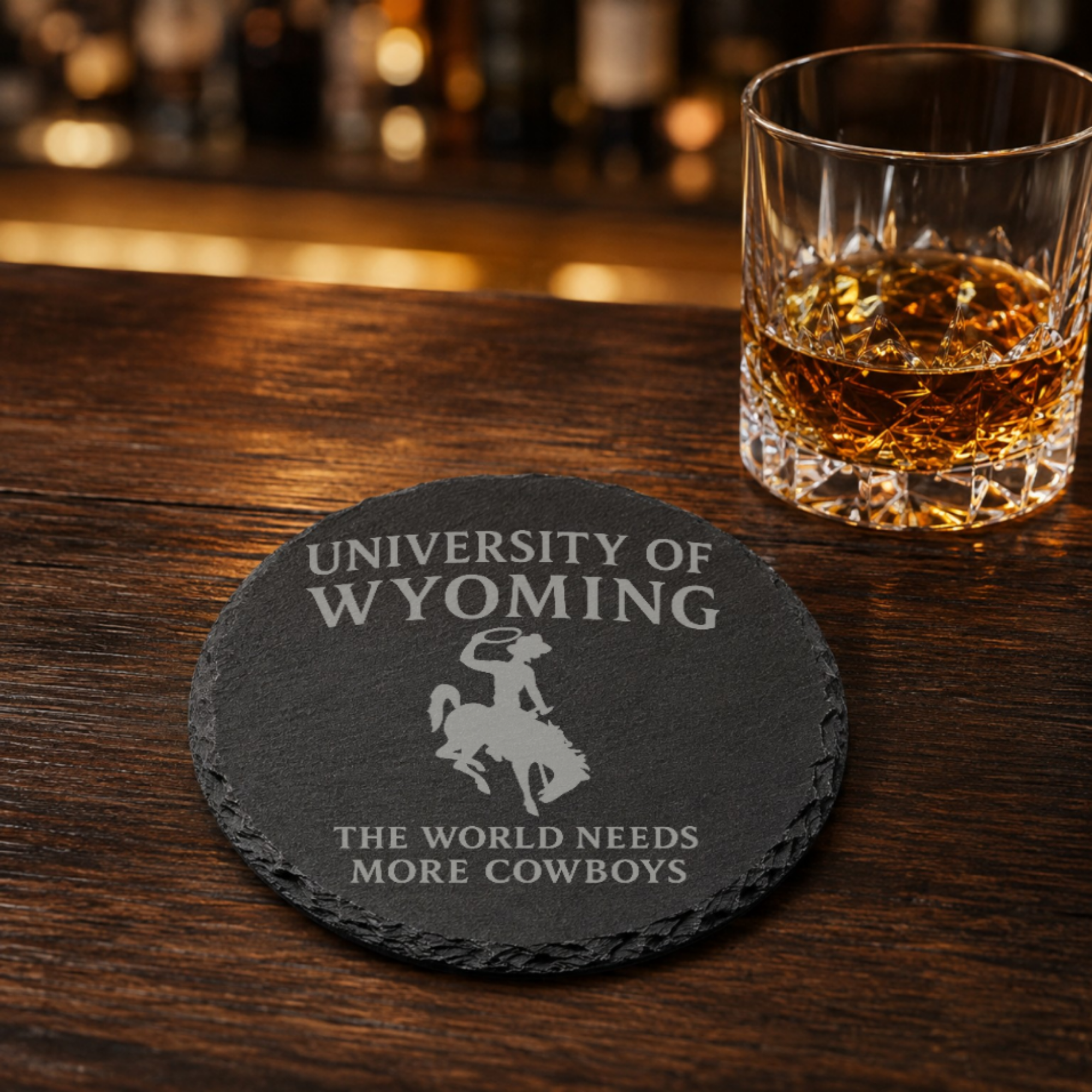 University of Wyoming Slate Coaster – "The World Needs More Cowboys" | Laser Engraved | Rustic Cowboy Gift - UW — Dandelion Design Co. — SlateStudioMedia:gallery:15 — 0101-UWGN_university_of_wyoming_slate_coaster_quot_the_world_needs_more_cowboys_quot_laser_engraved_rustic_cowboy_gift_uw_16_D02_round_whiskey_lifestyle.png
